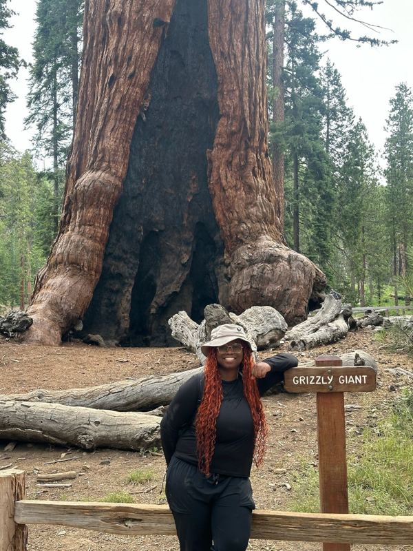 Nia smiling in front of the Grizzly Giant sequoia in Yosemite